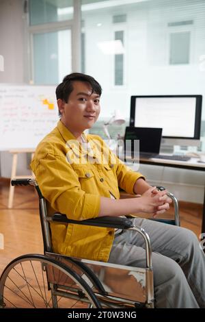 Glücklicher, stolzer junger asiatischer Mann mit Behinderung, der arbeitet Stockfoto