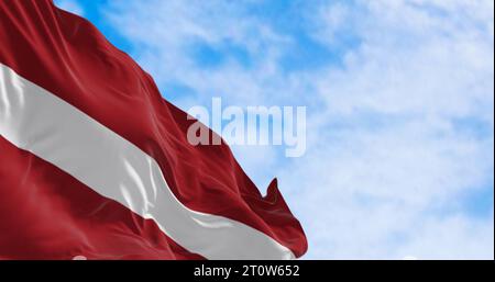 Nationalflagge der Republik Lettland winkt an einem klaren Tag im Wind. Rotes Feld mit einer weißen horizontalen Linie in der Mitte. 3D-Darstellung. Ripp Stockfoto