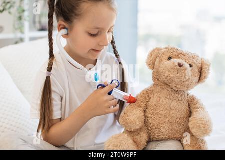 Kleines Kind, das Braunbären mit Spielzeugnadel injiziert Stockfoto