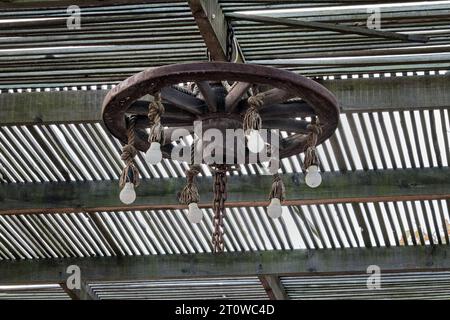 Antike Holzlampe aus Wagenrad, die an der Decke hängt. Stockfoto