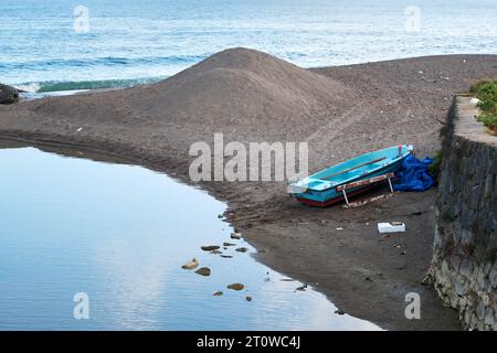 Blaues Fischerboot am Sandstrand und Meer. Stockfoto