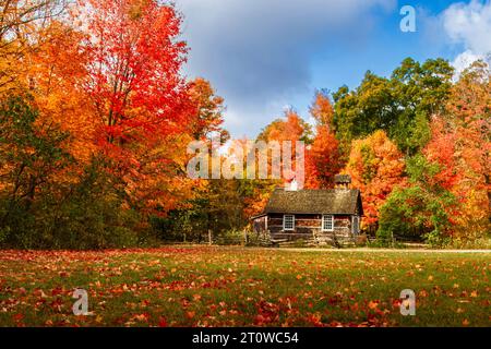 Herbstlandschaft - kleines Holzhaus unter den bunten Herbstbäumen, kanadischer Herbst, Herbst in Kanada, Herbstkonzept Stockfoto