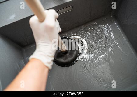 Augsburg, Bayern, Deutschland. September 2023. Handwerker versucht eine Verstopfung in einem Waschbecken mit einer Saugglocke zu lösen *** Handwerker versucht eine Verstopfung in einem Waschbecken mit einer Saugglocke zu lösen Credit: Imago/Alamy Live News Stockfoto