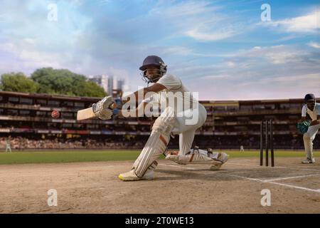 Cricketschläger, der während eines Cricketspiels auf dem Spielfeld einen Sweep-Schuss trifft Stockfoto