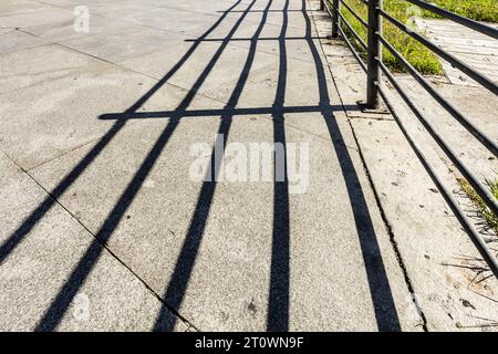 Schatten eines Metallzauns, der an die Granitfliesen genagelt ist Stockfoto