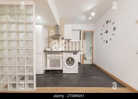 Apartment mit offener Küche mit weißen Möbeln und integrierten weißen Geräten Stockfoto