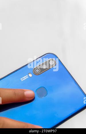 Foto eines kleinen asiatischen Kindes, das ein blaues Smartphone hält Stockfoto