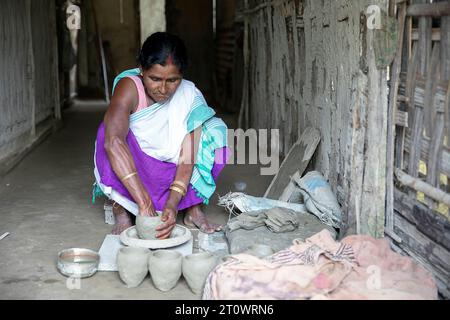Indische Frau macht Töpferei auf dem Boden in einem typischen Haus, Majuli, Assam, Nordostindien, Assam Stockfoto