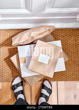 Stapel der gelieferten Papppakete auf einer Türmatte neben dem Eingang der Wohnung Stockfoto