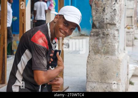 Ehrliches Porträt eines lächelnden kubanischen Mannes an einem verwitterten Steingebäude in Old Havanna. Stockfoto