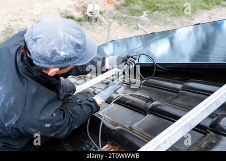 Elektriker, der Sonnenkollektorkabel auf dem Dach eines Hauses verbindet Stockfoto