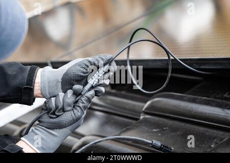 Hände eines Elektrikers, der Sonnenkollektorkabel auf dem Dach eines Hauses verbindet Stockfoto