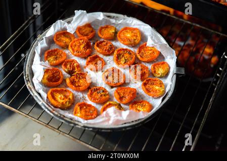 Schalen mit frischen Kirschtomaten auf Gestellen trocknen im Ofen Stockfoto