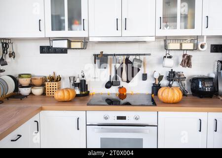 Dekor der weißen klassischen Küche mit Kürbissen für Halloween und Ernte. Herbststimmung im Innenraum, moderner Loft-Stil. Stockfoto