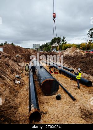 Verfahren zur Verlegung und Verbindung von Wasserversorgungs- oder Abwasserleitungen. Hebevorgänge im Bauwesen. Stockfoto