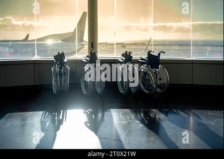 Rollstühle, die in der Nähe des Fensters im Wartezimmer des Flughafens geparkt sind Stockfoto