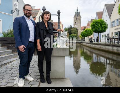 Memmingen, Deutschland. Oktober 2023. Die Künstlerin Cornelia Brader steht zusammen mit Oberbürgermeister Jan Rothenbacher (SPD) am Stadtbach neben der Bronzeskulptur der Katze Chicco, die sie schuf. Die burmesische Katze war in der schwäbischen Stadt bekannt und sehr beliebt. Anfang 2023 starb Chicco. So wurden Spenden für das Denkmal gesammelt, das ihm am Stadtbach gedenken wird. Quelle: Stefan Puchner/dpa/Alamy Live News Stockfoto