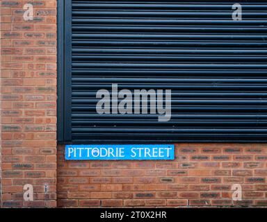 Straßenschild zur Pittodrie Street neben dem Pittodrie Stadium, Heimstadion des FC Aberdeen mit schwarzem Kühlergrill. Stockfoto