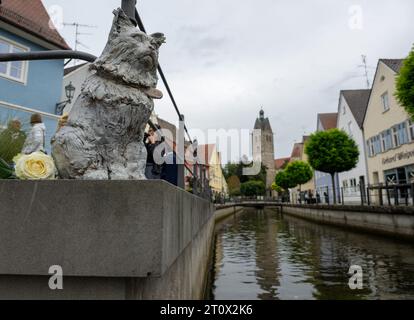 Memmingen, Deutschland. Oktober 2023. Das Denkmal für die berühmte Katze Chicco befindet sich an der Mauer am Stadtbach. Die burmesische Katze war in der schwäbischen Stadt bekannt und sehr beliebt. Chicco starb Anfang 2023. Als Ergebnis wurden Spenden gesammelt und die Memmingener Künstlerin Cornelia Brader schuf eine Bronzeskulptur der Katze zu seiner Erinnerung am Stadtbach. Quelle: Stefan Puchner/dpa/Alamy Live News Stockfoto