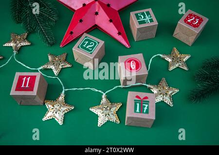 Handgefertigter Adventskalender: Basteln Sie Papierwürfel mit Zahlen auf einem leuchtend grünen Hintergrund. Weihnachtliche Tradition und festliche Dekoration Stockfoto