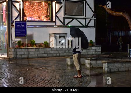 Srinagar, Indien. Oktober 2023. Ein Mann hält einen Schirm, während er während der Regenfälle in Srinagar, der Sommerhauptstadt von Jammu und Kaschmir, entlang der Straße spaziert. Quelle: SOPA Images Limited/Alamy Live News Stockfoto