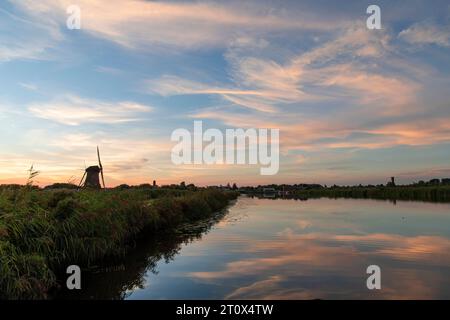 Blick auf den Sonnenuntergang über das ruhige Wasser mit Schilfbetten eines Kanals mit perfekter Reflexion der Sonnenuntergangswolken im Wasser neben der Silhouette des berühmten 18. Jahrhunderts Stockfoto