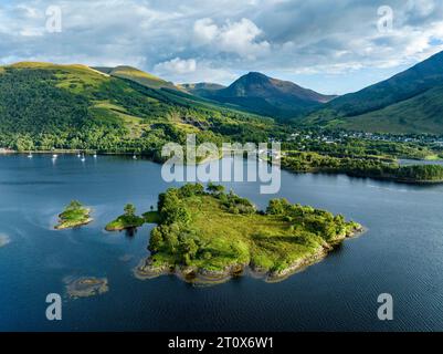 Aus der Vogelperspektive auf die Insel Eilean Munde, dahinter das Dorf Ballachulish mit dem Hafen und dem ehemaligen Schieferbruch im westlichen Teil von Stockfoto