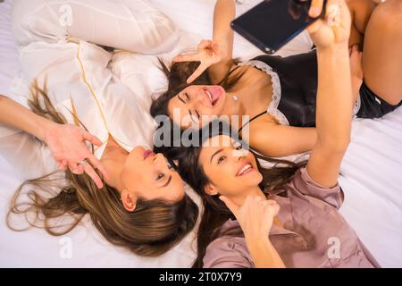 Lebensstil von kaukasischen Freunden im Urlaub in einem Hotel im Bett, fotografiert von oben, ein Selfie mit dem Telefon Stockfoto