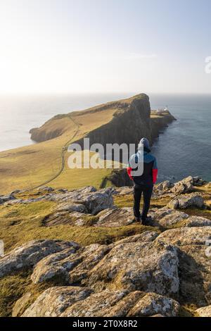 Ein Wanderer blickt auf den Neistpoint Lighthouse im Morgenlicht, Isle of skye, Großbritannien Stockfoto