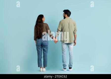 Rückansicht des östlichen Paares, das über blauen Hintergrund läuft Stockfoto