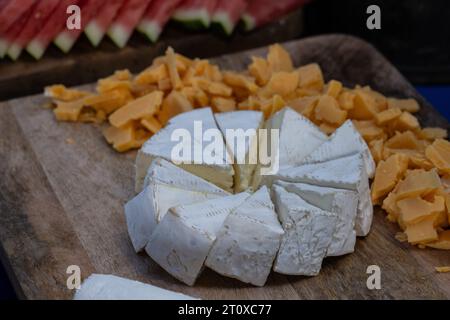 Partygäste können ein appetitliches Käserad auf einem Buffettisch aufstellen. Stockfoto