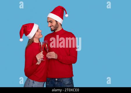 Glückliches Romantisches Paar In Santa Hats Clinking Champagnergläsern Stockfoto