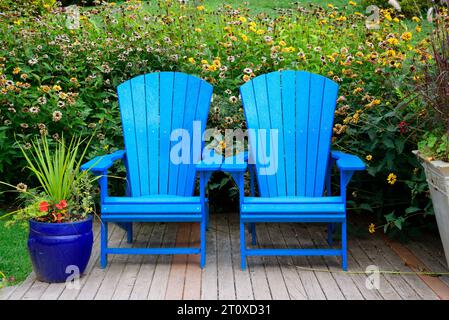 Zwei blaue Adirondack-Stühle in einem Garten Stockfoto