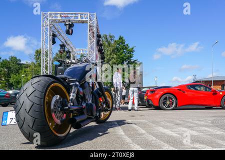 Liepaja, Lettland, 20. Juli 2023: Europäische Ferrari-Autobesitzer-Veranstaltung und öffentliche Autoausstellung, kundenspezifische Motorräder und Ferrari 488-Spider-Rückansicht, blauer Himmel Stockfoto