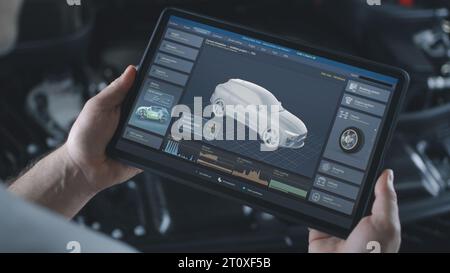 Männlicher Techniker hält einen digitalen Tablet-Computer. Simulation von Autodiagnosen und Aerodynamiktests in Echtzeit auf dem Bildschirm. 3D-Animation der Software mit virtuellem 3D-Elektrofahrzeugmodell. Stockfoto
