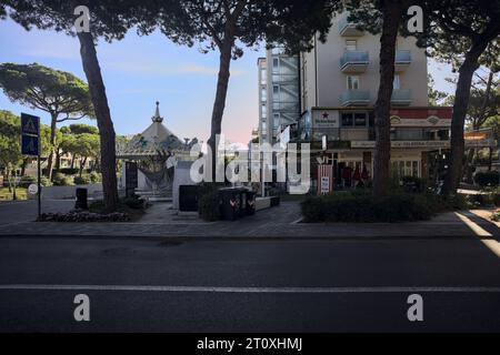 Fröhlich gehen Sie herum und stehen unter zwei Kiefern neben einer Brücke über einen Wasserbach in einer italienischen Stadt an einem sonnigen Tag Stockfoto