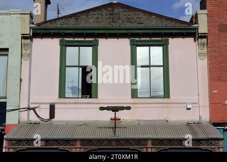 997 rosafarbene Zementwand und geneigtes Schieferdach der viktorianischen Handelsterrasse in der Brunswick Street. Melbourne-Australien. Stockfoto