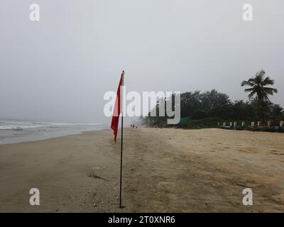 Rote Flagge, um Schwimmer vor der Gefahr zu warnen, in den ausgegrenzten Gebieten zu schwimmen, die für das Schwimmen am Strand von Benaulim im indischen Bundesstaat Goa unsicher sind Stockfoto