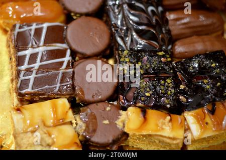 Verschiedene kleine kleine Tortenstücke mit verschiedenen Belägen und gefüllt mit verschiedenen Füllungen, Schwammkuchen mit brauner und weißer Schokolade, Karamell, Marmelade, Stockfoto