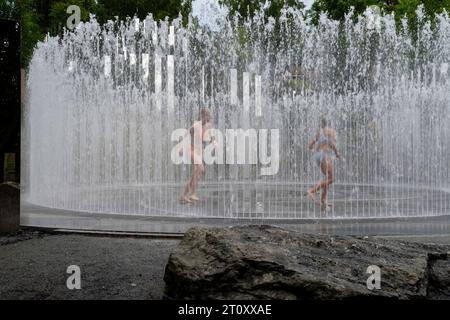 Zwei Mädchen spielen in einem Brunnen. Blick auf Kunstwerke im Kistefos Museum, einem Skulpturengarten im Freien in der Nähe von Jevnaker, Viken, Norwegen. Stockfoto