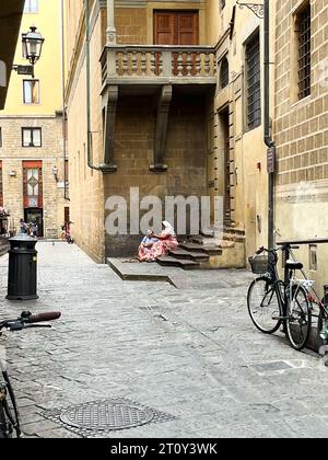 Florenz, Utaly. September 2023. Zwei Frauen betteln und sitzen auf einer kleinen Treppe in Florenz. Hochwertige Fotos Stockfoto