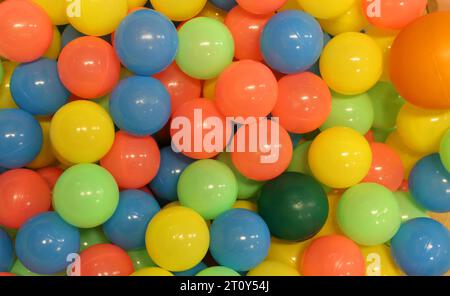 Eine Sammlung von bunten Plastikkugeln, die in einem Kinderballplatz oder einem unterhaltsamen Aktivitätszentrum gefunden werden. Kreisrunde runde bunte Kugeln in einer Spielgrube. Kinder haben Spaß Stockfoto