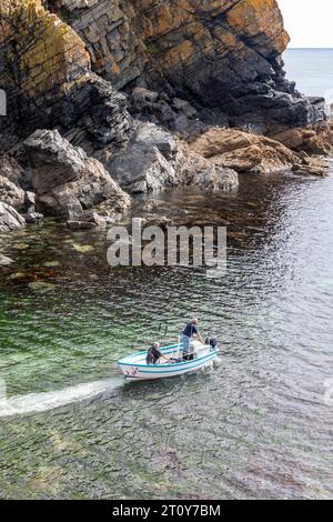 Cadgwith Dorf auf der Lizard Peninsula, Cornwall, England Fischer in einem kleinen Fischerboot verlassen die Bucht Stockfoto