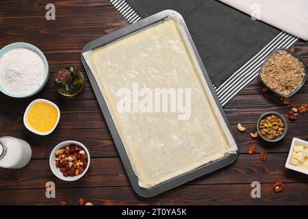 Ich mache köstliche Baklava. Backpfanne mit Teig und Zutaten auf Holztisch, flach liegend Stockfoto