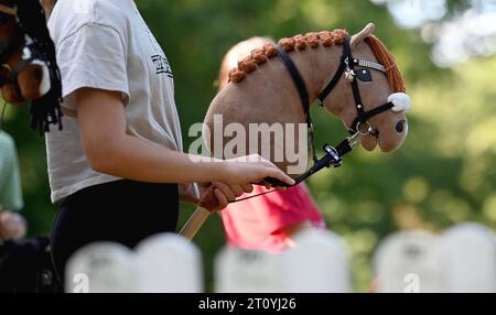 Berlin, Deutschland. September 2023. Ein Mädchen hält ihr Hobbypferd auf dem Hobbypferdekurs im Berliner Volkspark Wuhlheide. Hobbyreiten ist ein angesagter Sport, bei dem Elemente des Reitsports, wie Dressur oder Springreiten, mit einem Hobbypferd nachgebildet werden. Der Sport hat seinen Ursprung in Finnland. Quelle: Carla Benkö/dpa/Alamy Live News Stockfoto