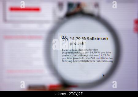 Leipzig, Deutschland. Oktober 2023. Durch eine Lupe sehen Sie die Worte „79 % Sollzinsen pro Jahr“ für eine Überziehungsfazilität bei einer Sparkasse. Die Verbraucherschutzminister der länder und des Bundes bestehen auf einer Obergrenze für Überziehungszinsen. Nach Ansicht der Stiftung Warentest sind Überziehungseinrichtungen zu teuer, wenn sie mehr als 15,25 Prozent Zinsen Kosten. Quelle: Jan Woitas/dpa/Alamy Live News Stockfoto