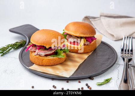 Heiße Burger mit Salat und Gemüse auf einem Holzbrett Stockfoto