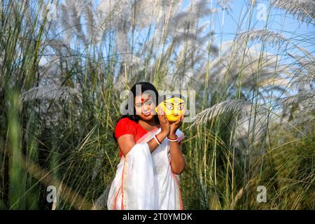 Das Modemodell Rima Bhattacharya posiert während des Agomoni Concept Outdoor Fotoshootings in einem mit Catkins oder Kashful gefüllten Gebiet rund 60 km von Kalkutta entfernt, während es einen traditionellen indischen Saree trägt und das Gesicht des Durga-Idols in der Hand hält. Das Model Rima Bhattacharya posiert für ein Foto für die Fotoserie, die auf dem Thema Durga Puja Vibes in Indien basiert. Rima Bhattacharya, ein Model und Prominente in der bengalischen Mode- und Fernsehbranche, arbeitet mit der Fotoserie zusammen, um Durga Puja zu fördern. Die Fotoserie wird von einer Gruppe von Fotografen organisiert die die vor- Stockfoto