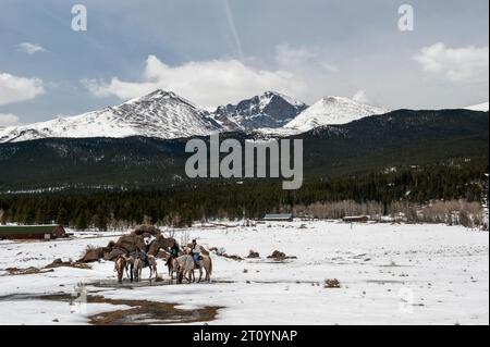 Eine Gruppe von Reitern tränkt ihre Pferde unterhalb des Longs Peak von Colorado Stockfoto