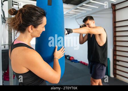 Ein persönlicher Trainer führt einen jungen Turner beim Boxtraining. Stockfoto